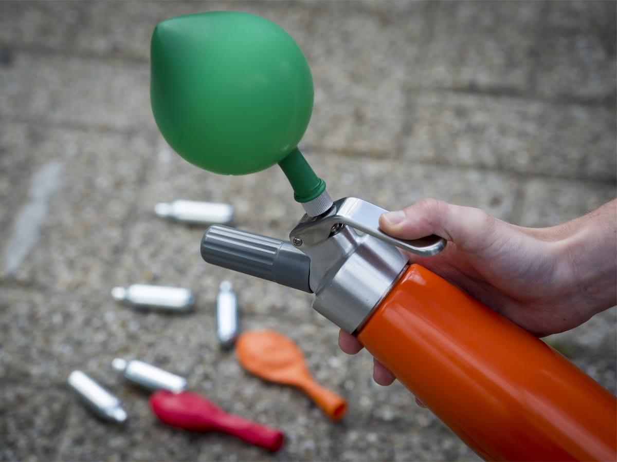 Cream charger used to inflate a green balloon