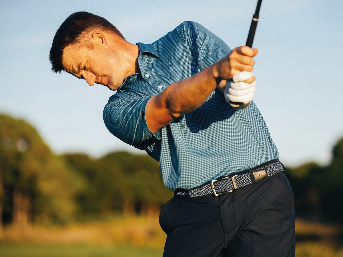 A golfer in a blue shirt and black pants