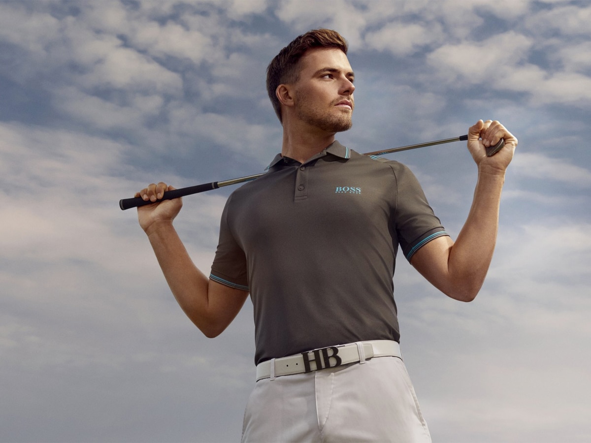 A golfer in a grey Hugo Boss shirt, white belt and pants