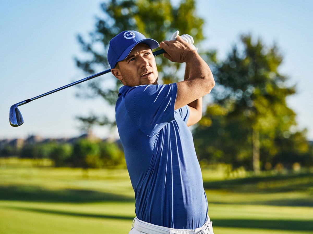 A golfer in a blue shirt, white pants, and a blue cap