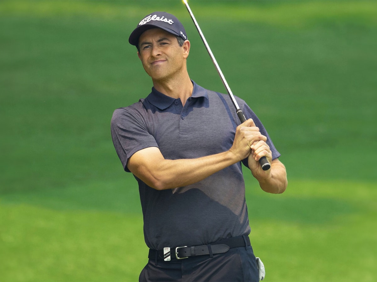 A golfer in a dark blue shirt, cap, and pants