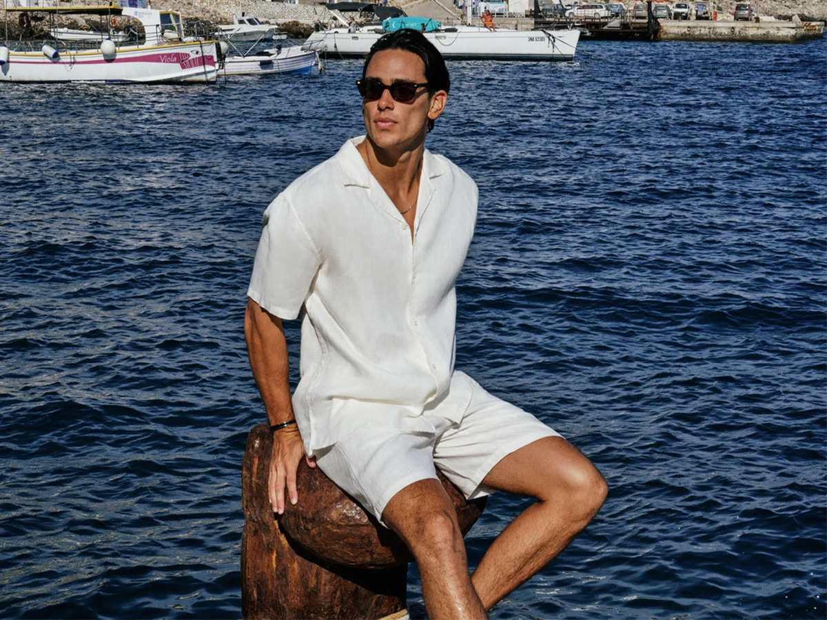 Male model wearing sunglasses and all white shirt and shorts