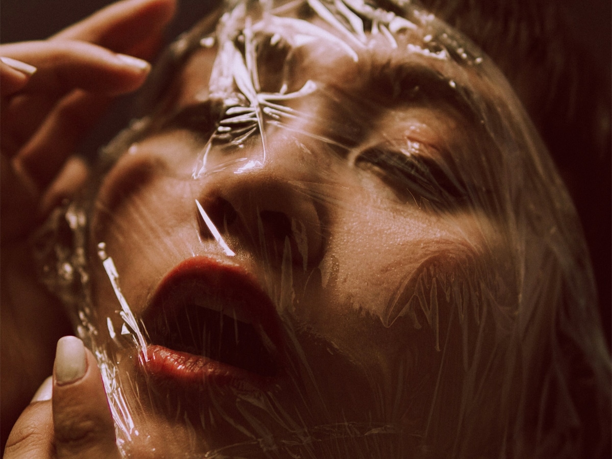 Face of a woman covered by a transparent plastic with her mouth open