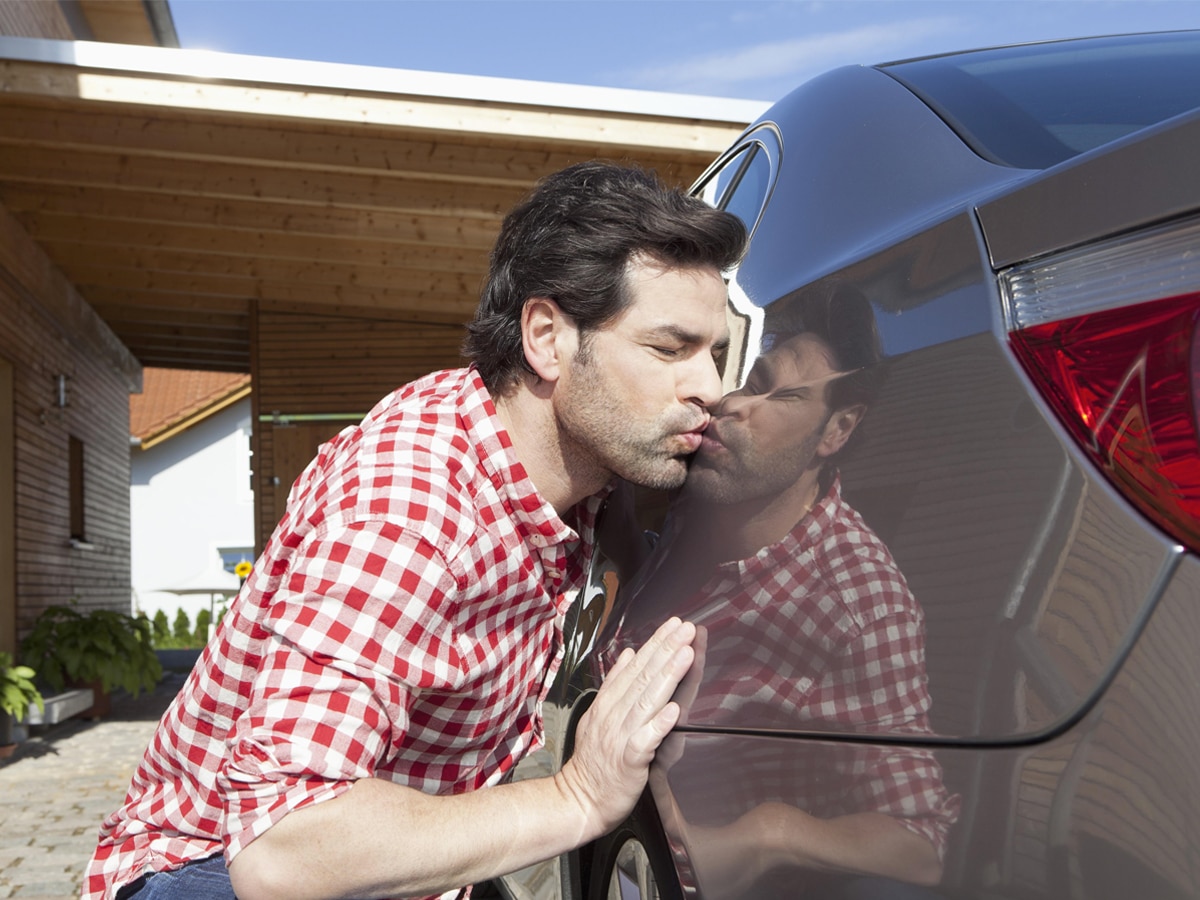 A man kissing the side of a car