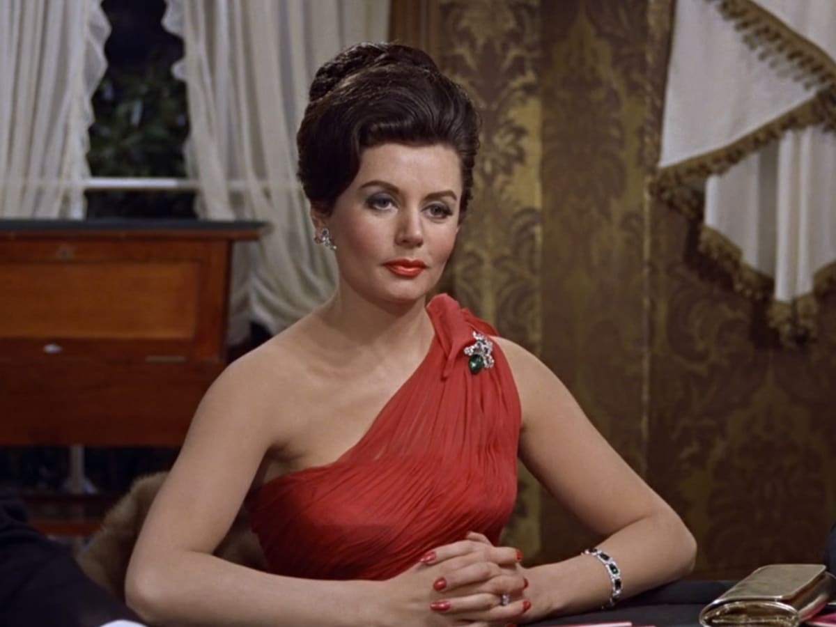 Eunice Gayson in a red dress with her hands intertwined