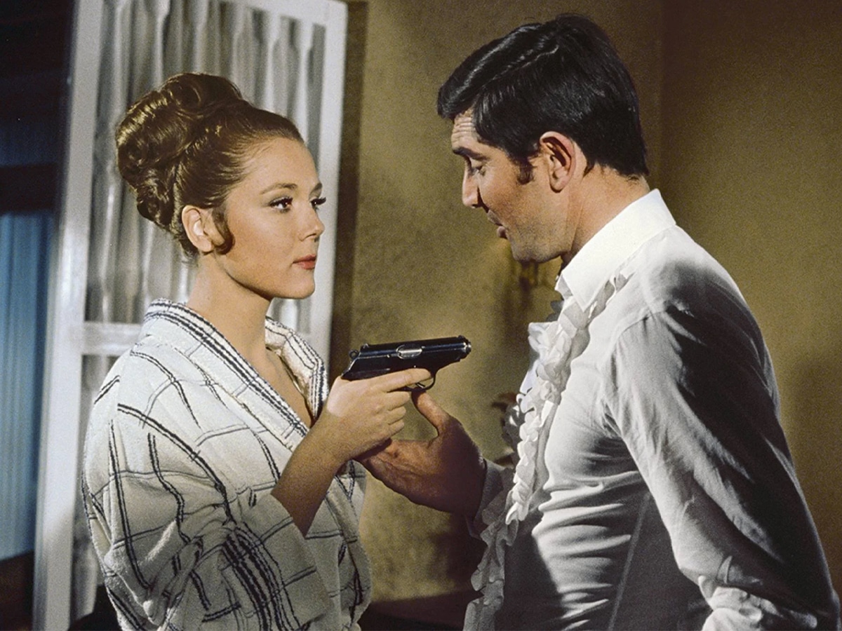 Diana Rigg pointing a gun at George Lazenby