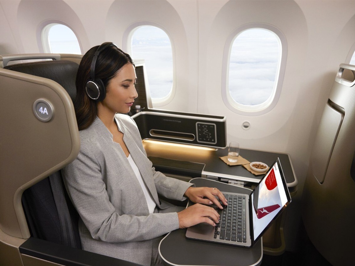 Woman on a plane browsing the Qantas website on her laptop