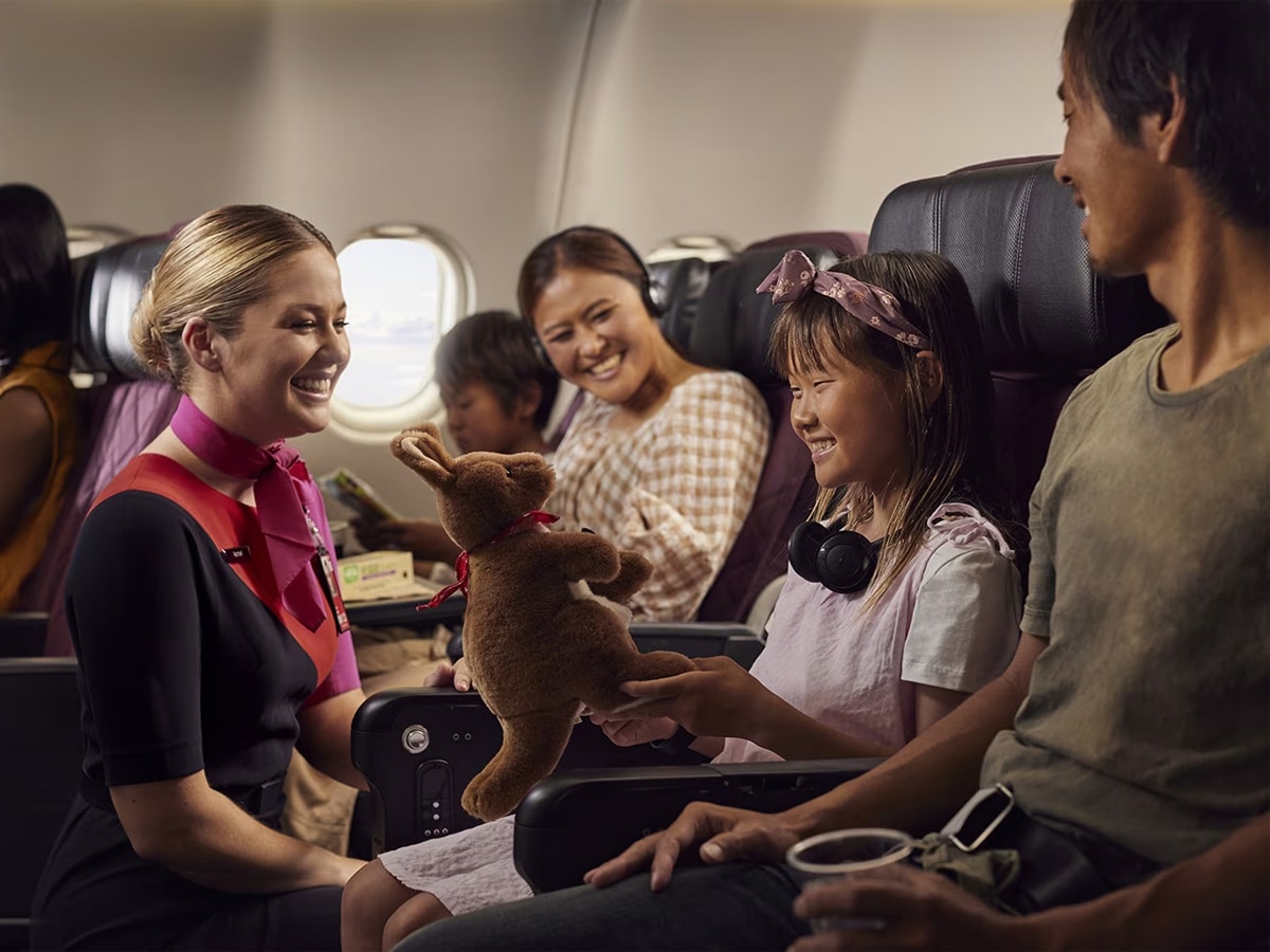 Girl with her family receiving a kangaroo plushie from a female flight attendant