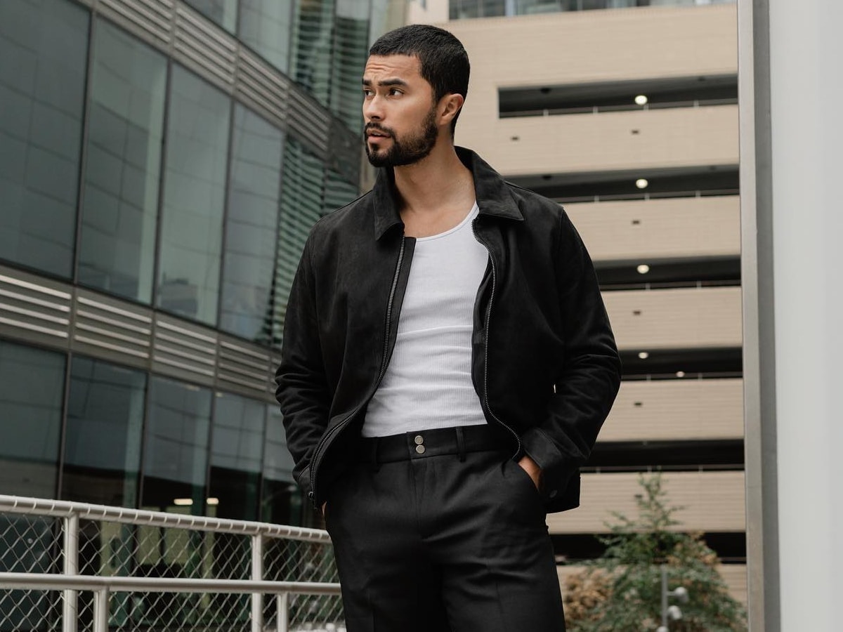 Male model in a white top underneath a black jacket and black pants