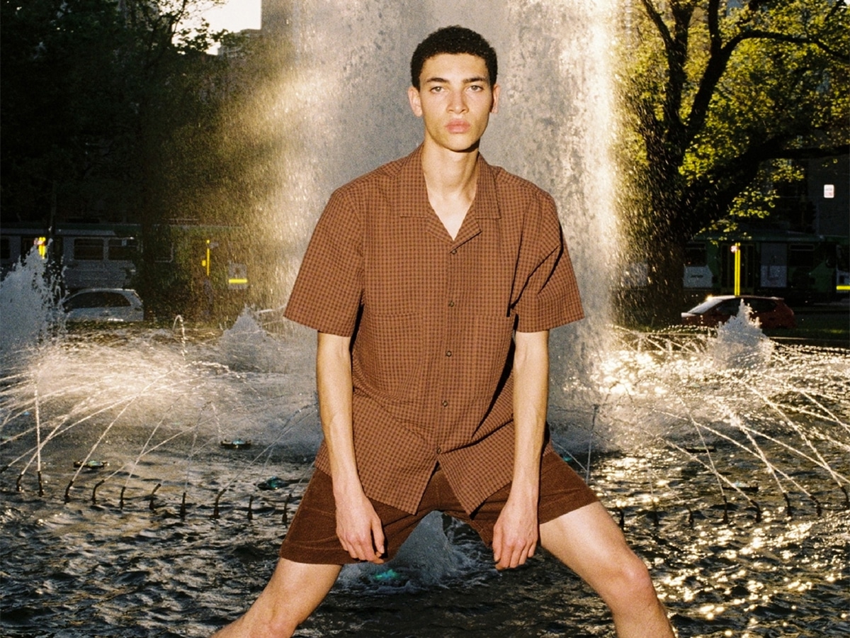 Male model in a plaid brown shirt and brown velvet shorts