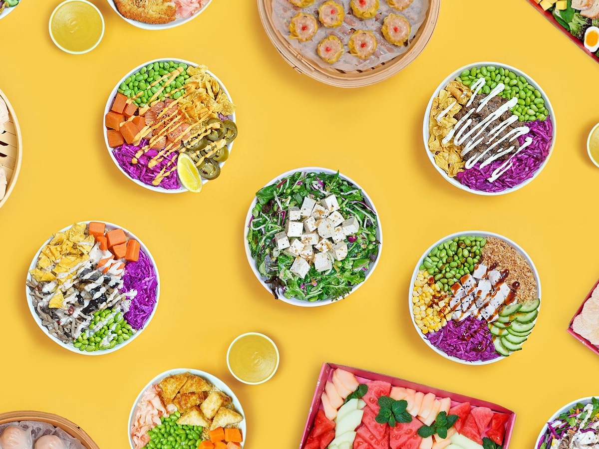 Overhead shot of multiple poke bowls on a yellow background