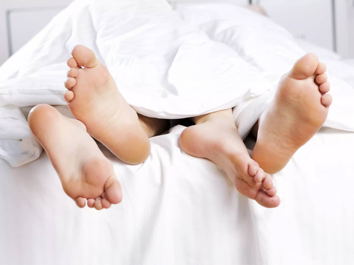 Couple's feet sticking out of end of bed
