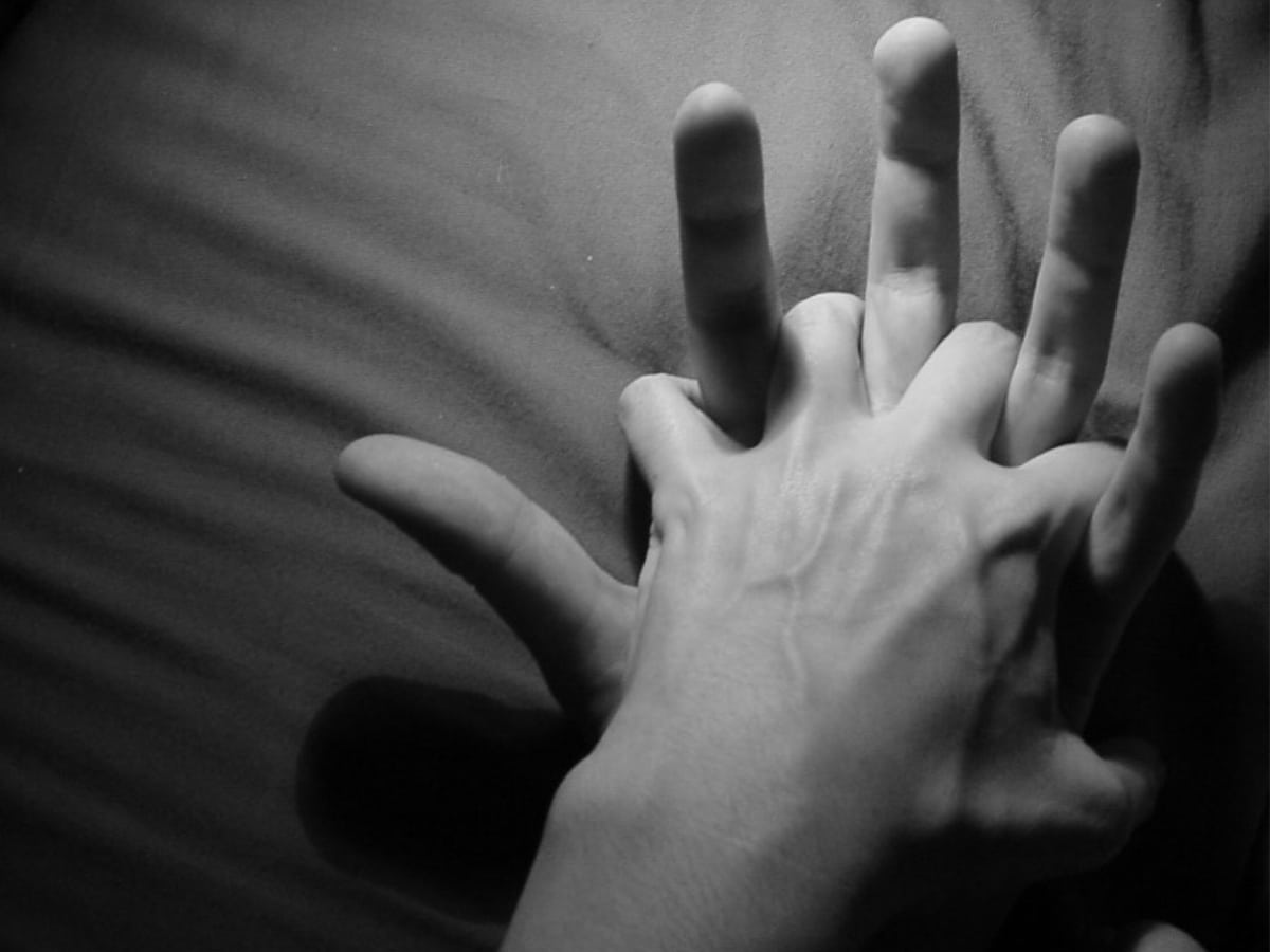 Greyscale image of couple's intertwined hands
