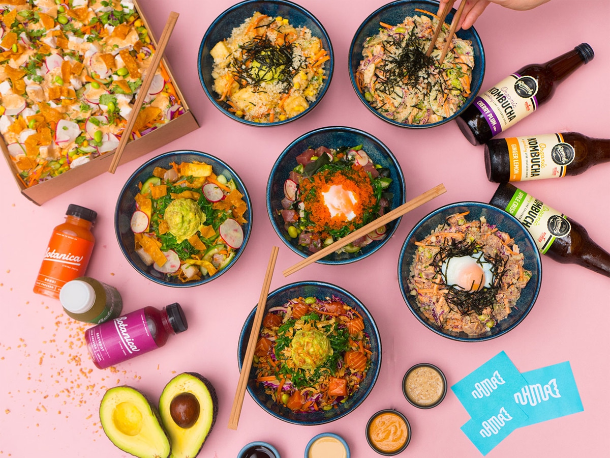 Six poke bowls with drinks and a box of poke set on a pink background