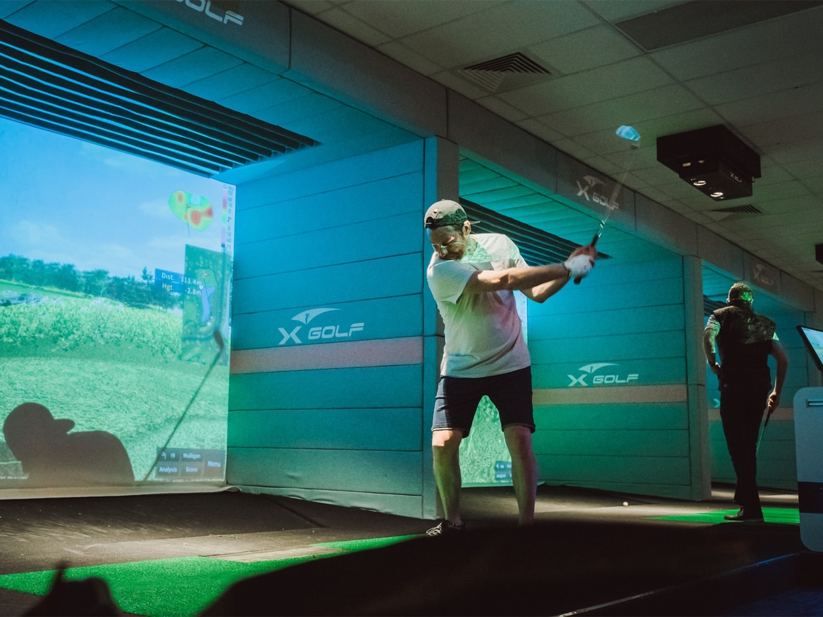Man hitting a golf ball at indoor golf simulator