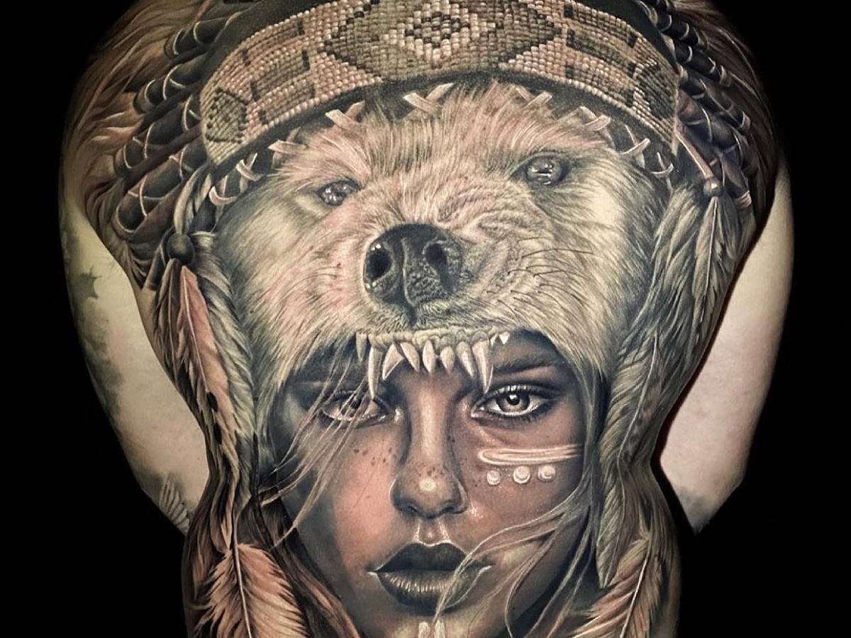 Tattoo of a woman's face inside a bear's mouth on a man's back
