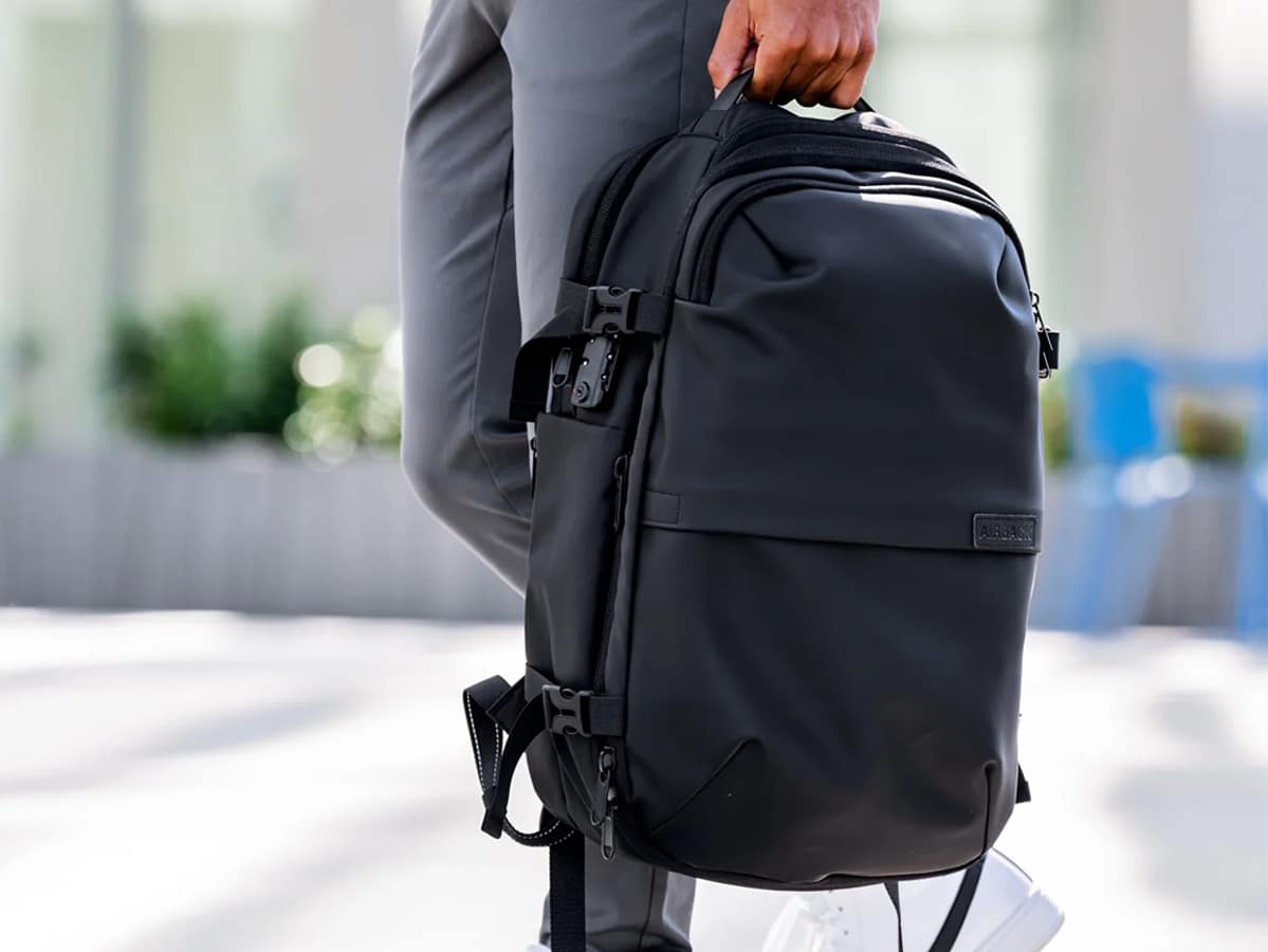 Man carrying the Airback Matt Black backpack with one hand