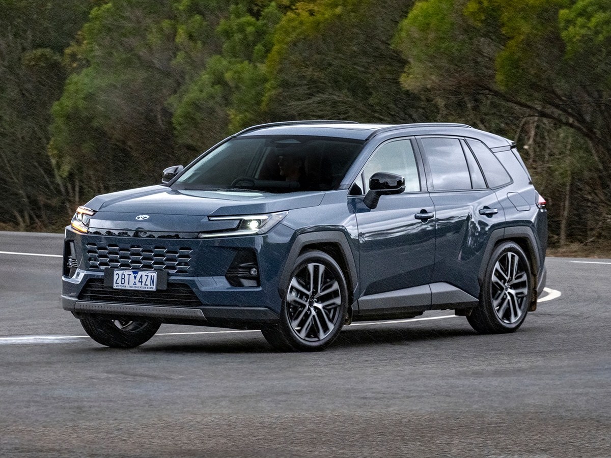 2026 Toyota RAV4 in grey driving on a winding road with trees in the background.