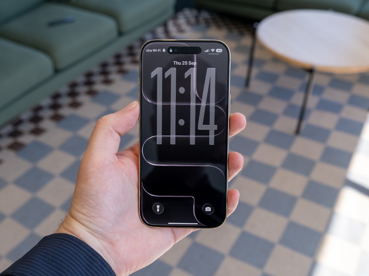 iPhone 17 Air in white held in hand, displaying lock screen with time in a modern living room.