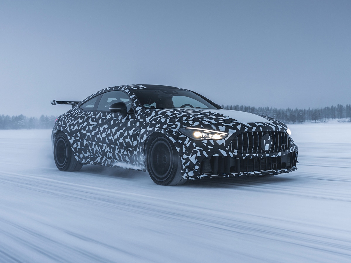 Mercedes-AMG CLE Hammer prototype driving on snowy terrain with camouflage pattern and rear spoiler.