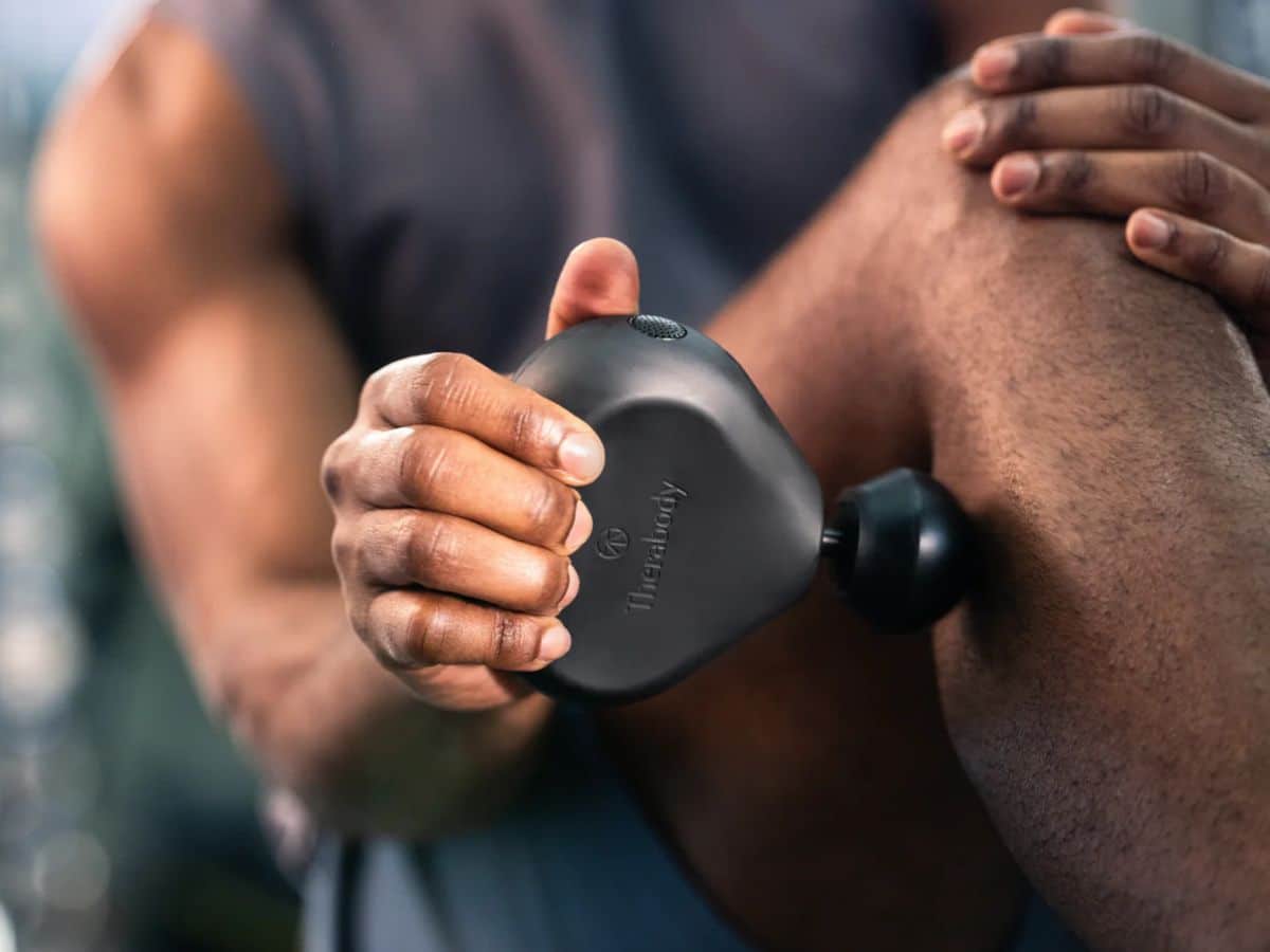 A close-up of the ultra-portable TheraGun Mini handheld percussion therapy device, in its standard black color, designed for travel-friendly muscle recovery.