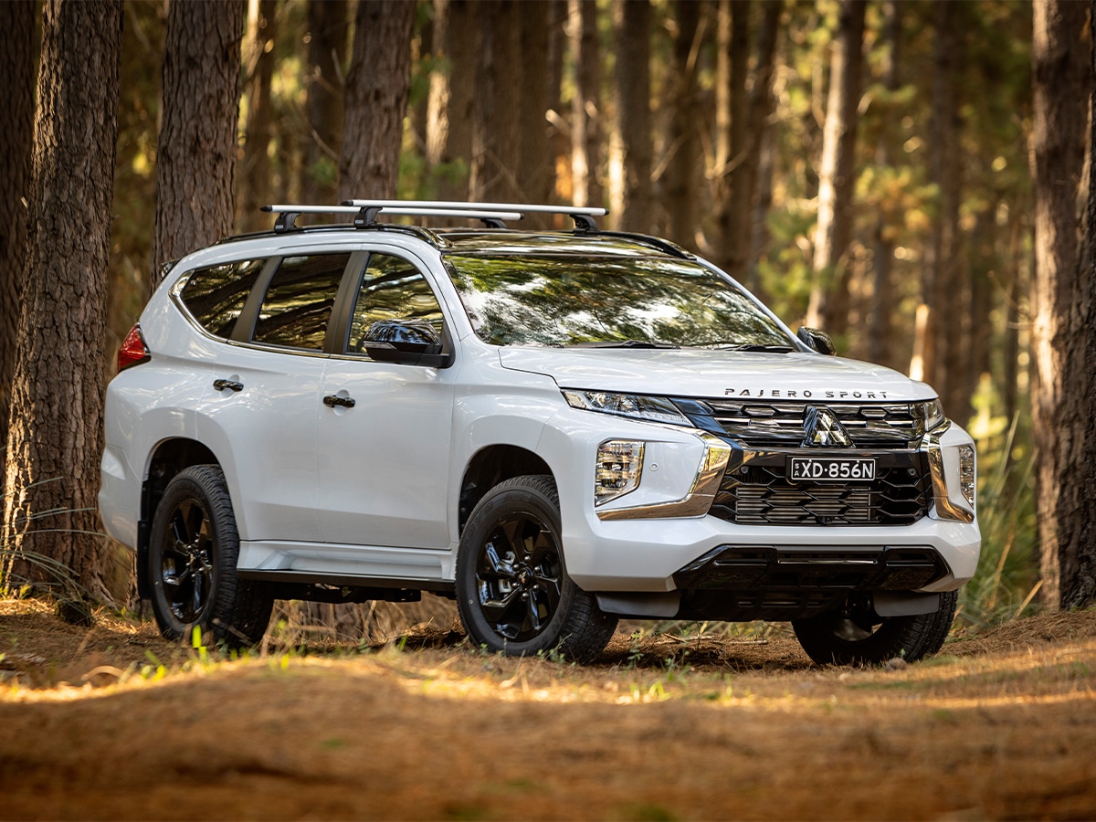 White Mitsubishi Pajero Sport parked in a forest setting