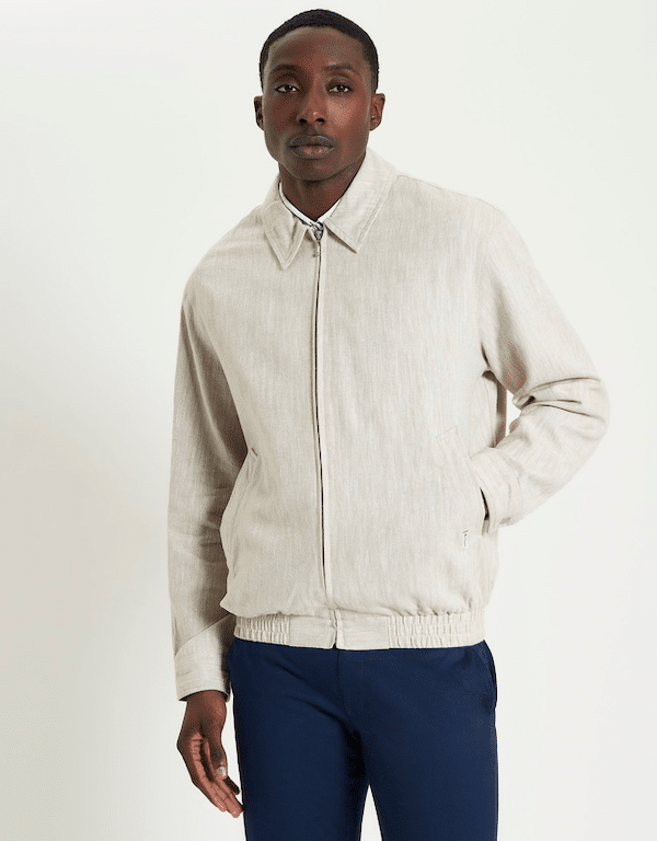 Model in a lightweight Ben Sherman woven linen blouson jacket in beige, perfect for transitional men's office wear.