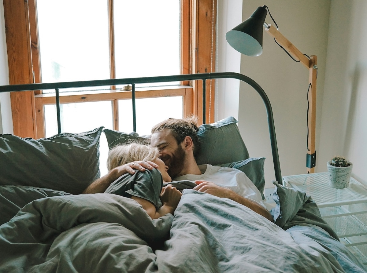 A couple sitting together in bed reflecting on their relationship intimacy after having kids