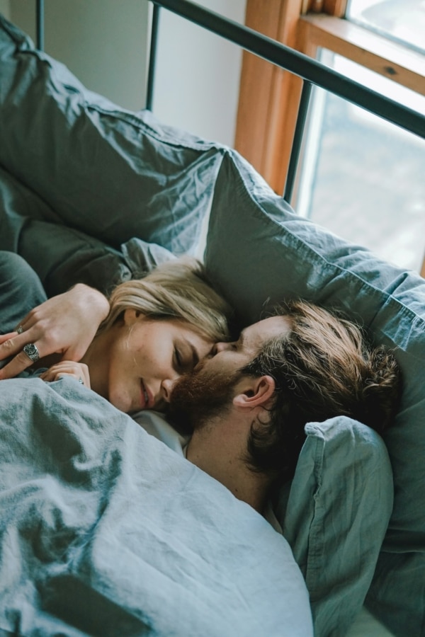 Couple lying in bed as man kisses woman's head