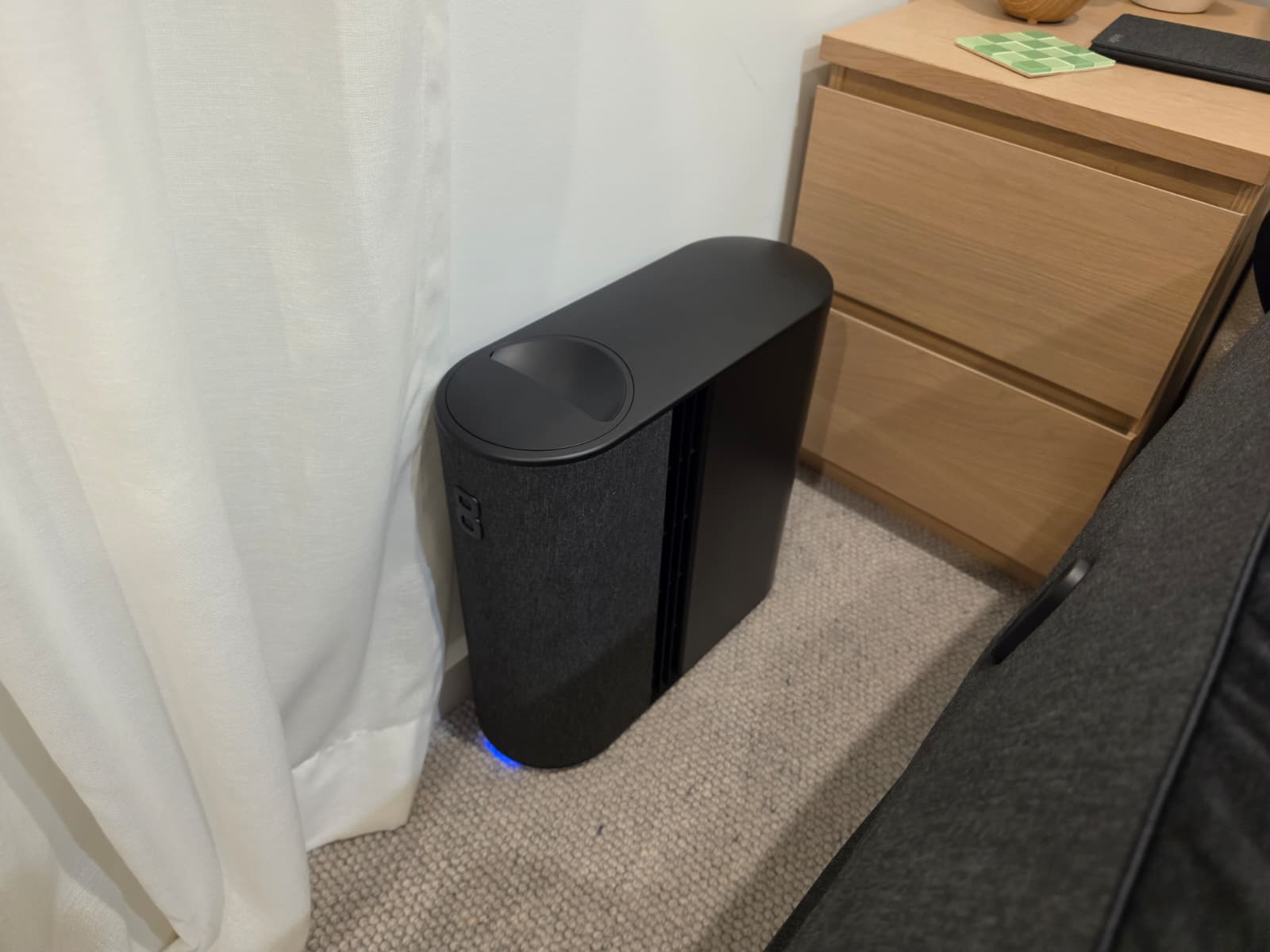 The Eight Sleep Pod 5 Hub standing on the floor beside a bedside table