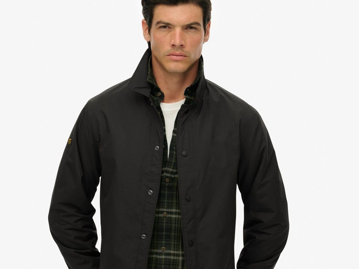 Man wearing the black Superdry nylon coach jacket over a check shirt