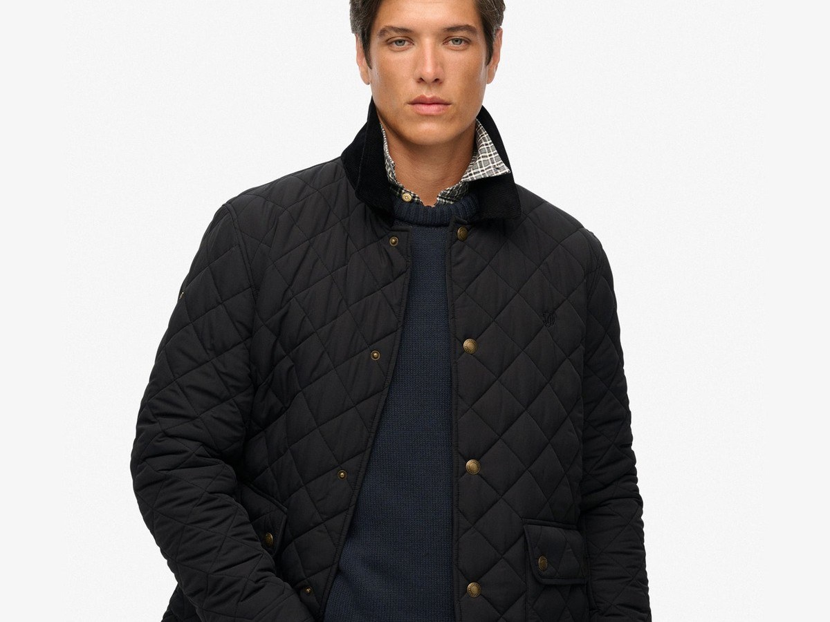 Man wearing the black quilted Superdry Estate coach jacket over a dark jumper