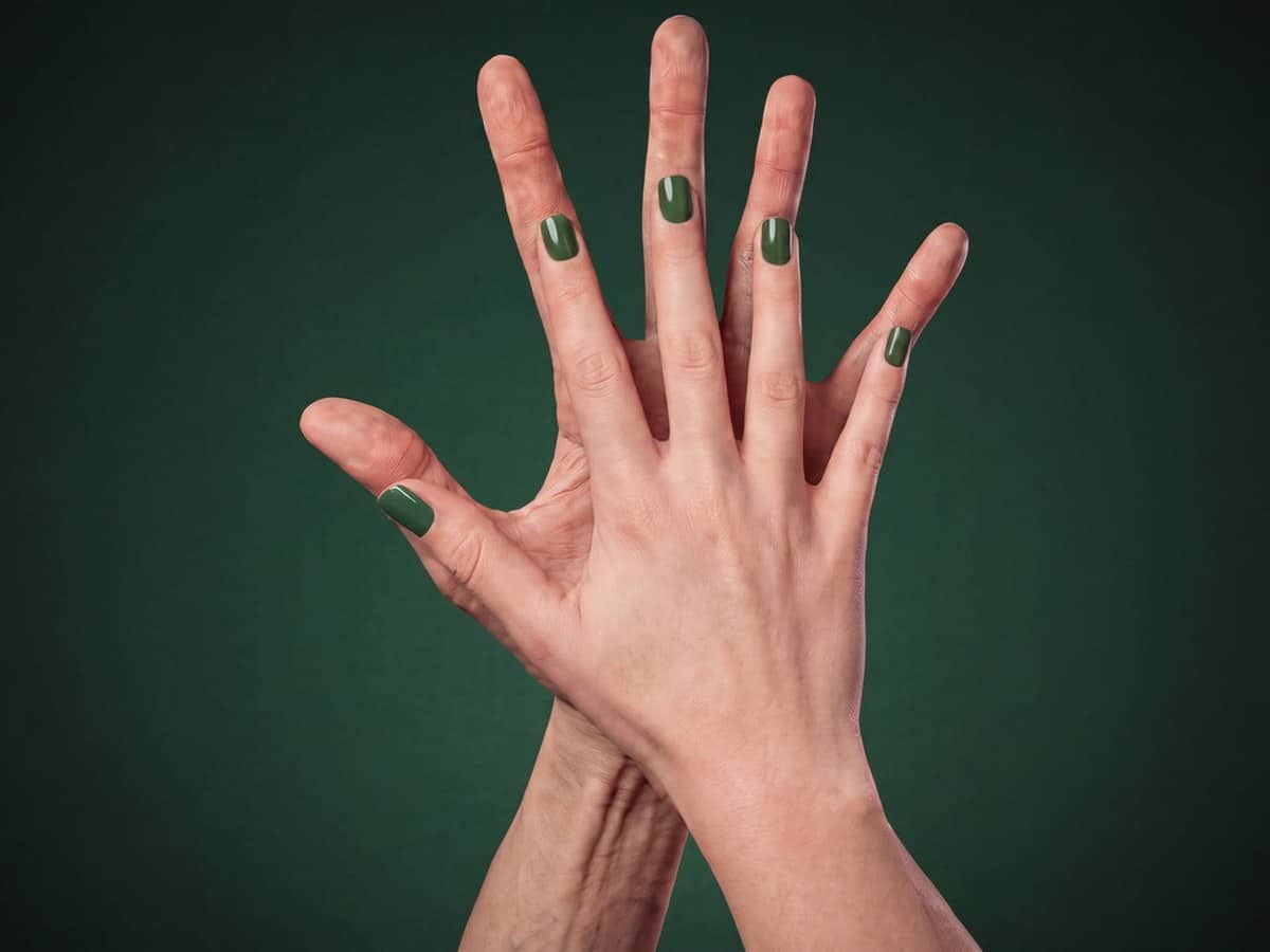 Two hands raised palm to palm against a dark green background showing off their size