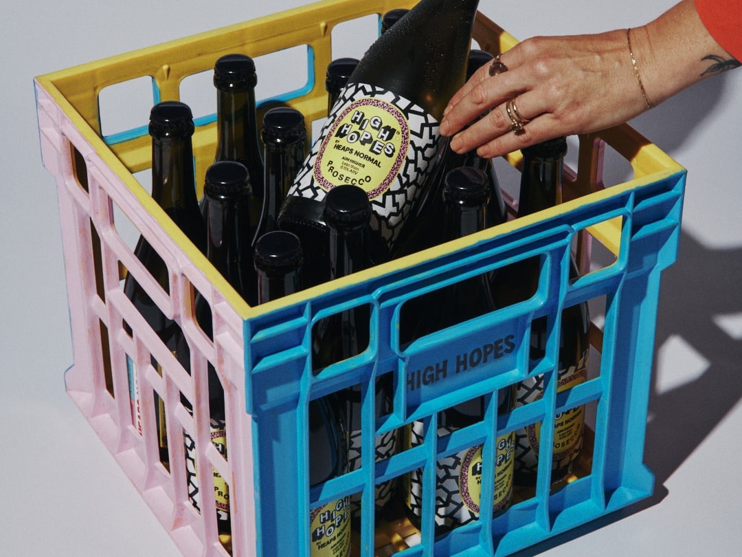 Hand placing a High Hopes bottle into a crate stamped HIGH HOPES