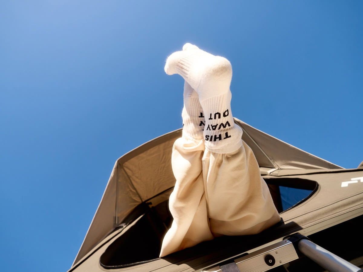 Legs in This Way Out socks poking out of a Dometic rooftop tent