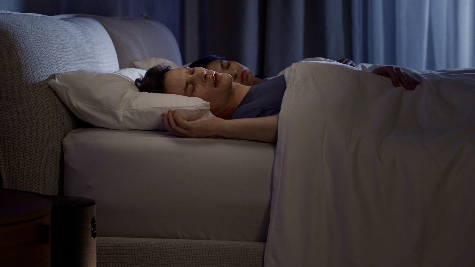 A couple sleeping on an Eight Sleep Pod, each side of the bed set to a different temperature