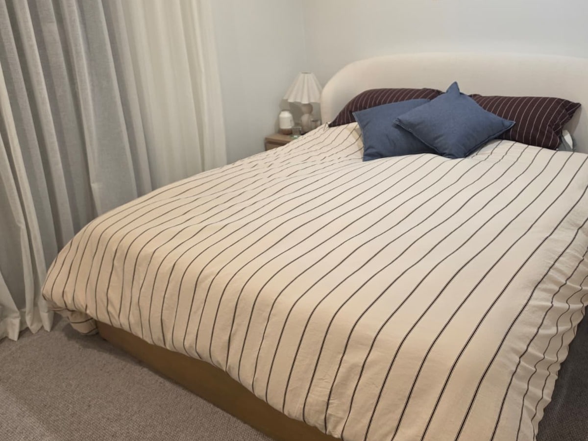 The Eight Sleep Pod 5 installed on a made-up king bed with a striped quilt
