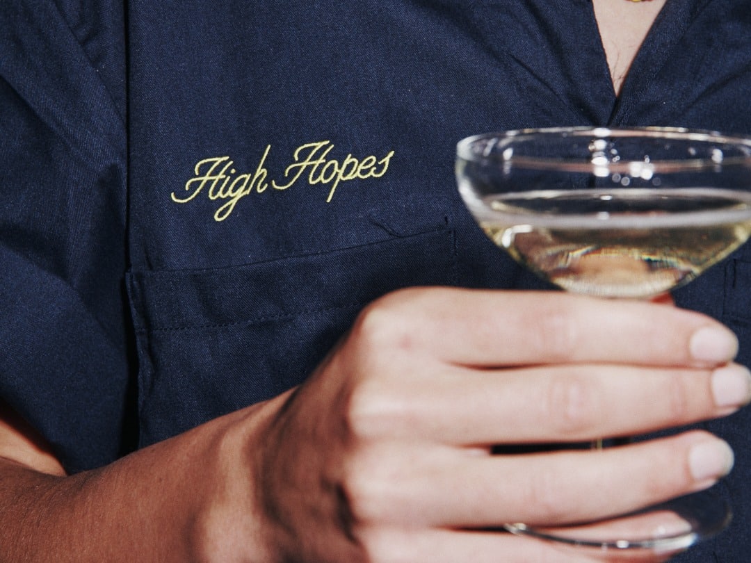 Embroidered High Hopes workwear shirt with a coupe glass of sparkling wine