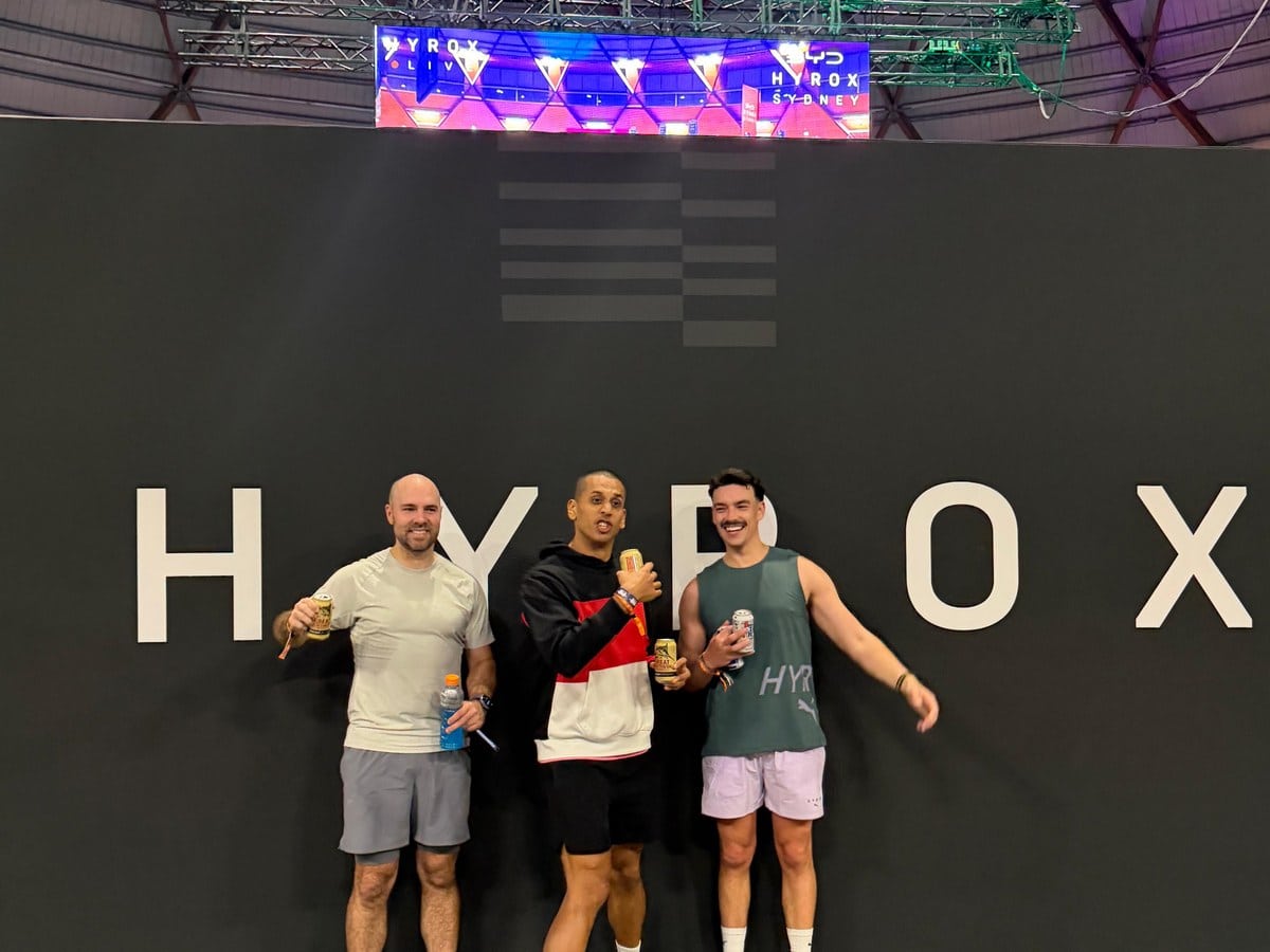 Three finishers in front of the HYROX Sydney signage wall