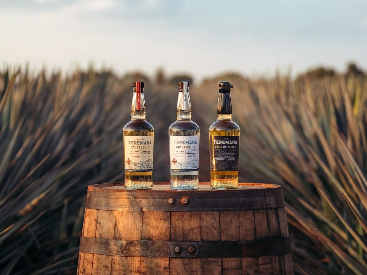 Teremana Blanco, Reposado and Anejo bottles lined up on a barrel in the Jalisco Highlands agave fields