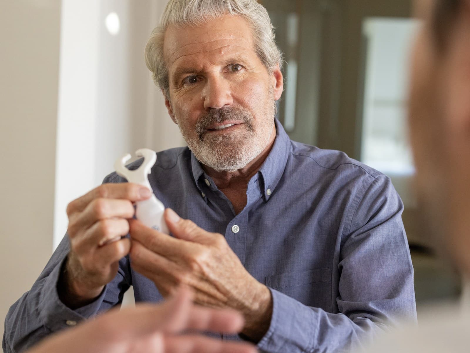 A man holding the Spring Sleep eXciteOSA device and its mouthpiece.