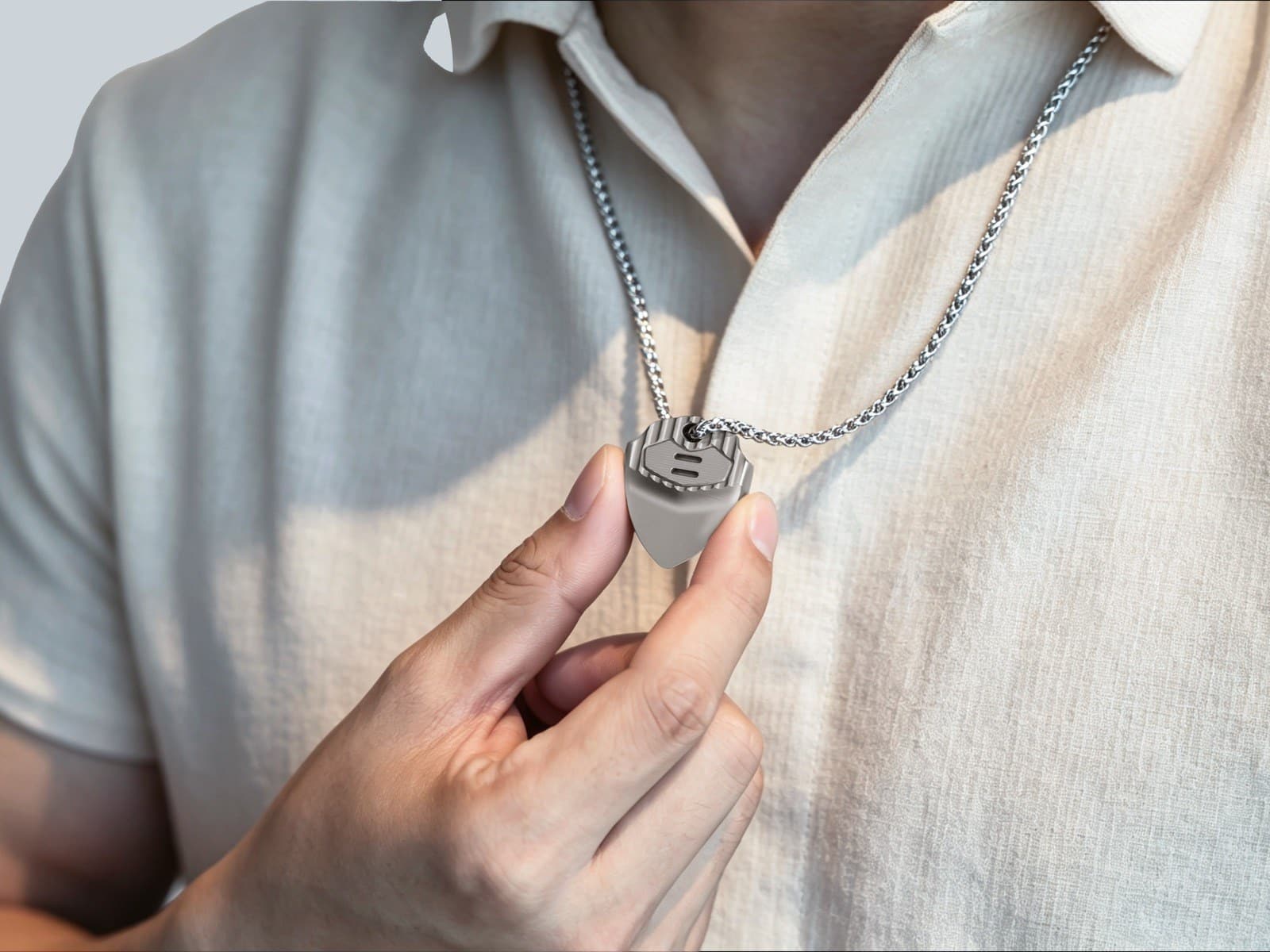 A person in a pale shirt holding an EchoTi pick worn on a neck chain