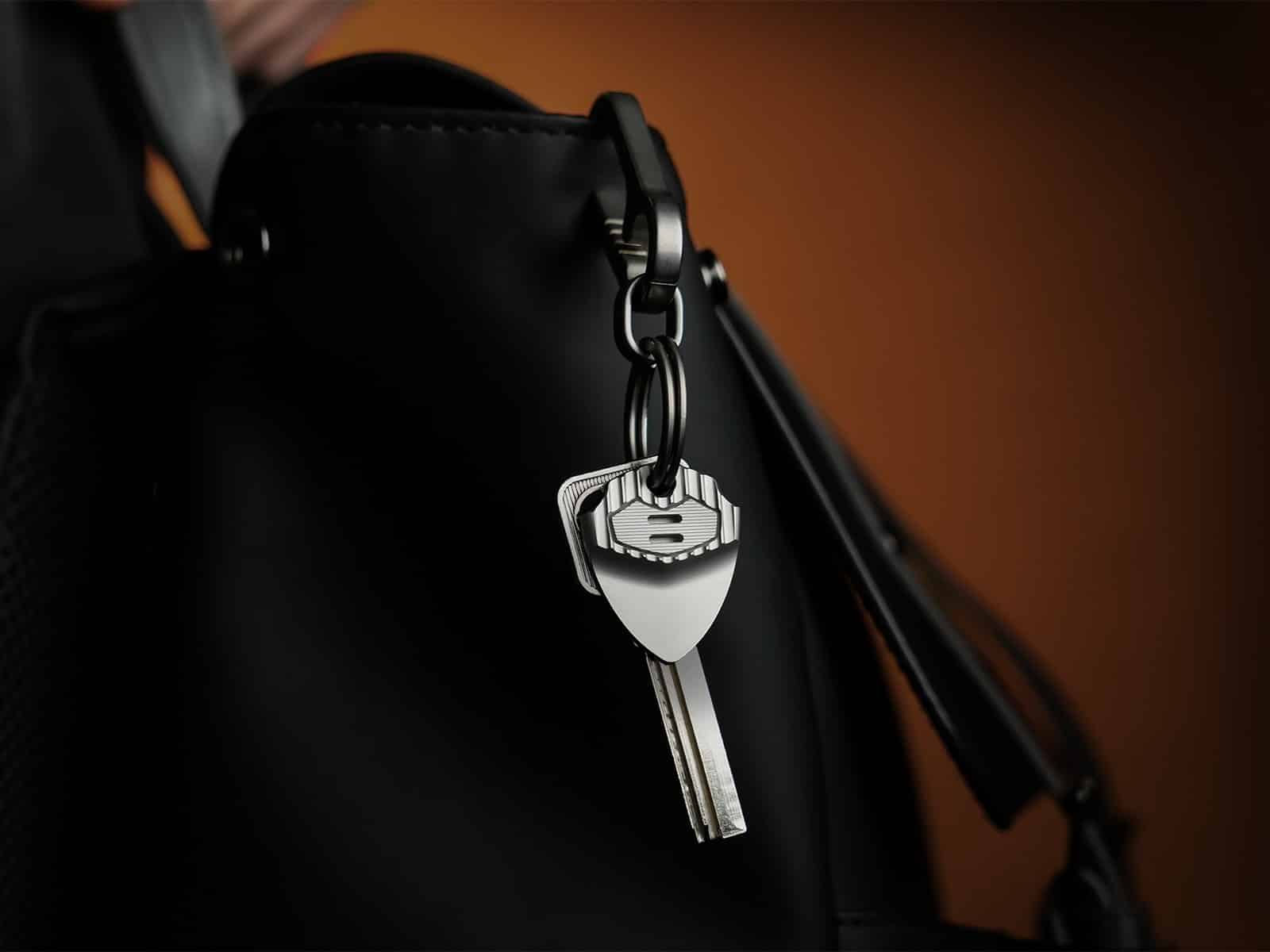 An EchoTi pick on a keyring with a key, clipped to a black bag
