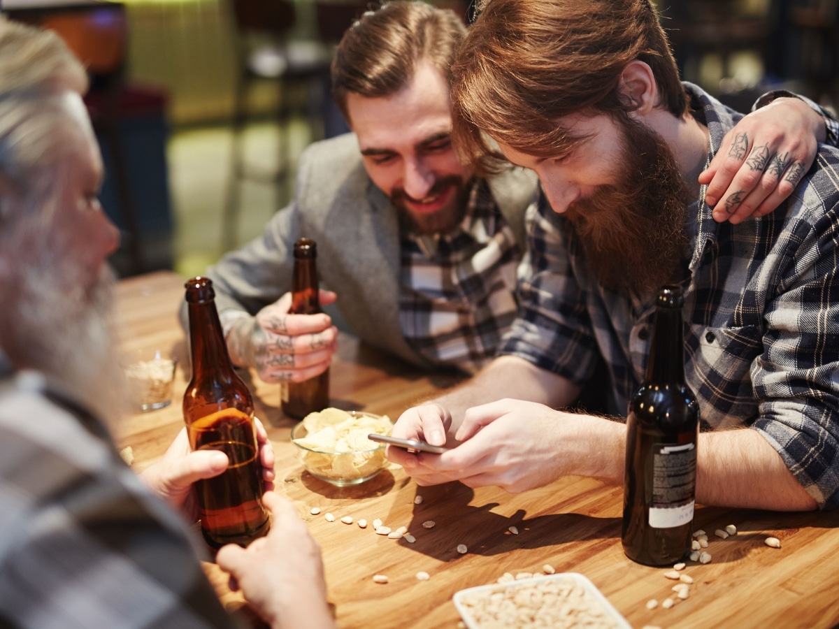 Men on their phone enjoying a drink at a pub