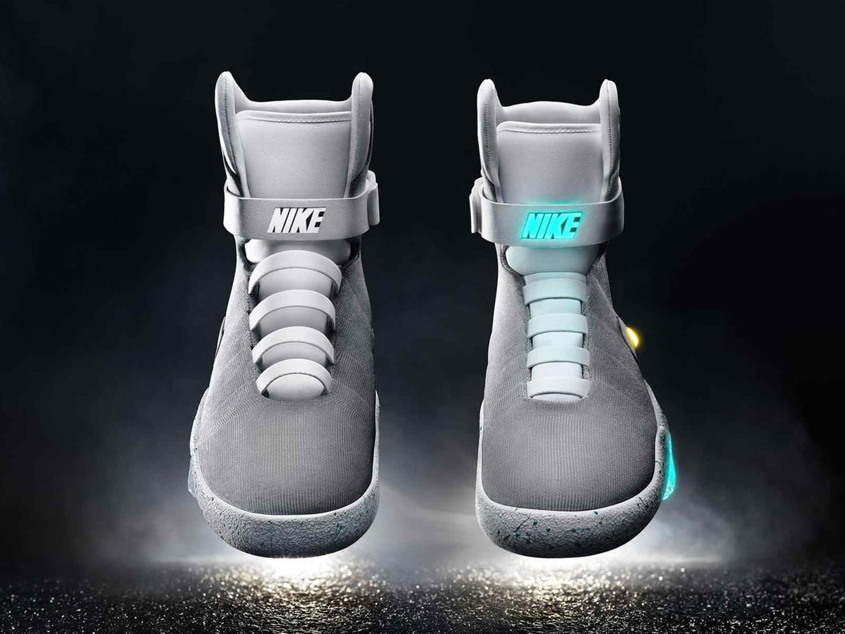 Front view of two Nike MAG shoes, one with a white strap and one with an illuminated NIKE strap