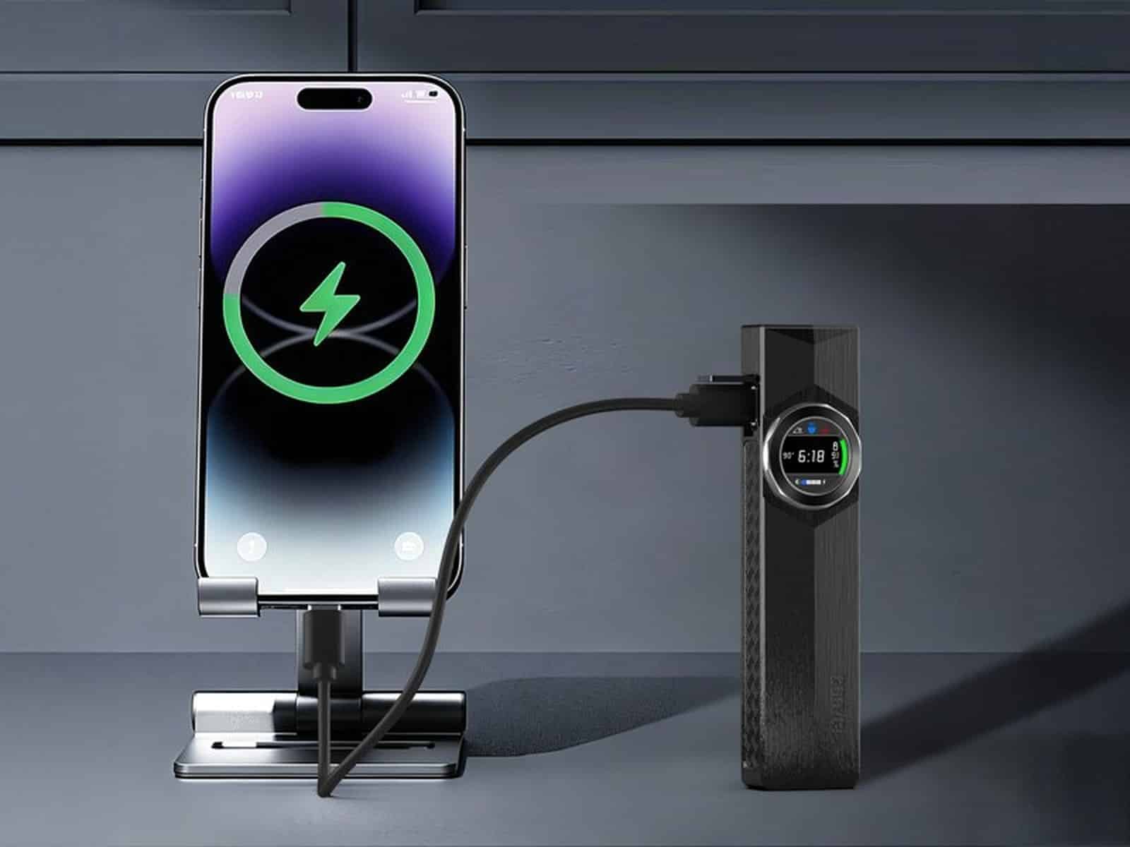 TorchNova on a benchtop, connected by a cable to a smartphone in a stand that shows a green charging ring on screen