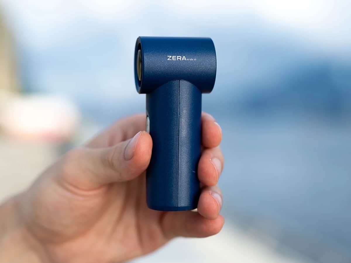 A hand holds the ZERA mini with a natural setting behind it