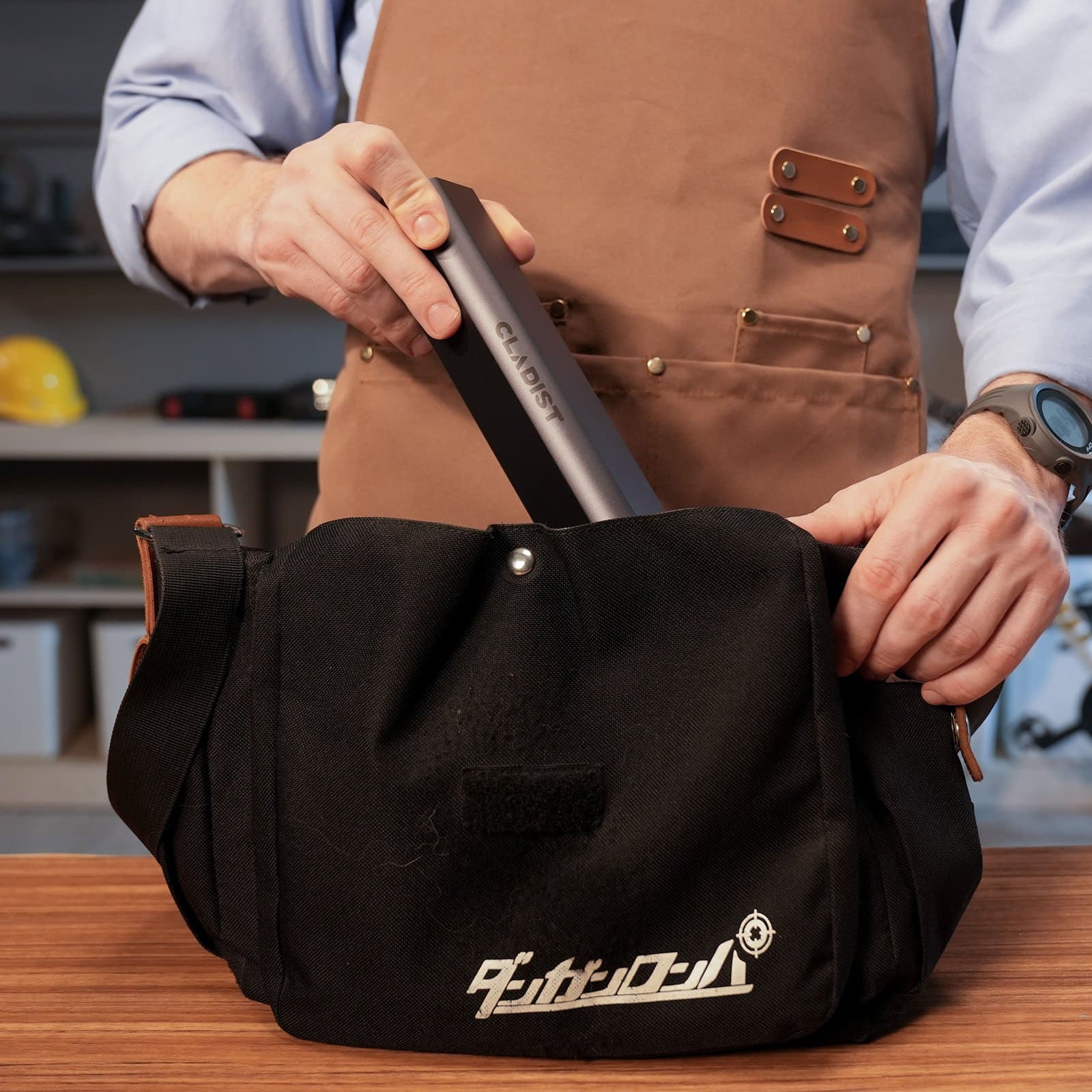 Cladist Titan aluminium case being slid into a black canvas messenger bag