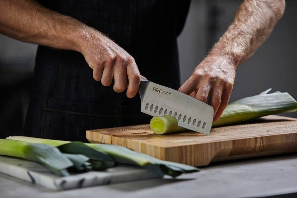 Slicing leeks with a Furi santoku knife on a timber chopping board
