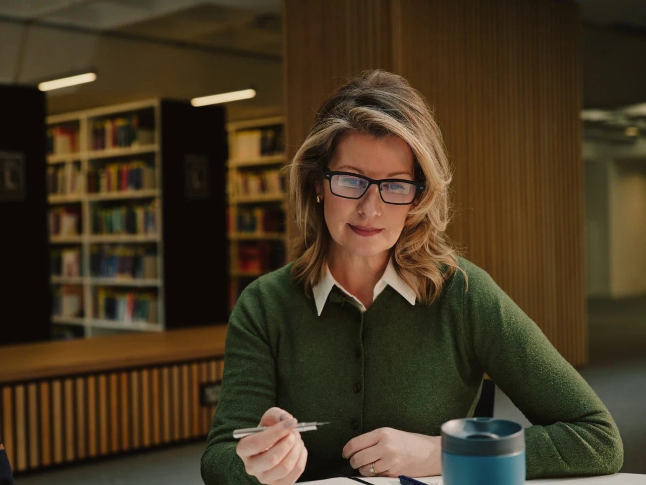 Woman wearing MemoMind One glasses while working at a desk in a library